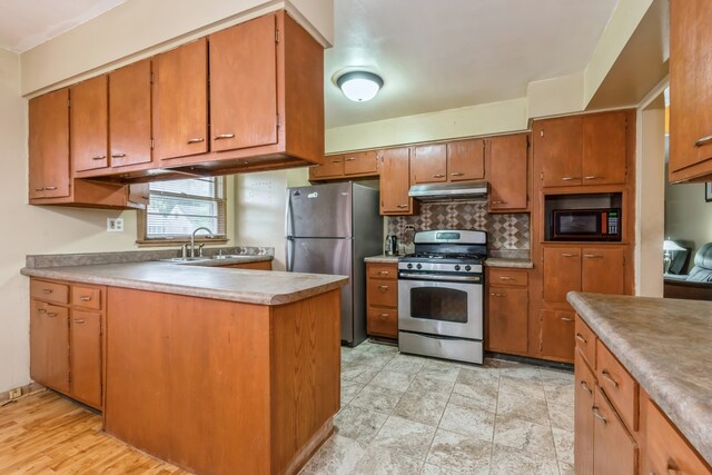 kitchen featuring appliances with stainless steel finishes, sink, tasteful backsplash, and light hardwood / wood-style flooring