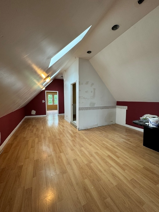 bonus room with light hardwood / wood-style floors and lofted ceiling with skylight