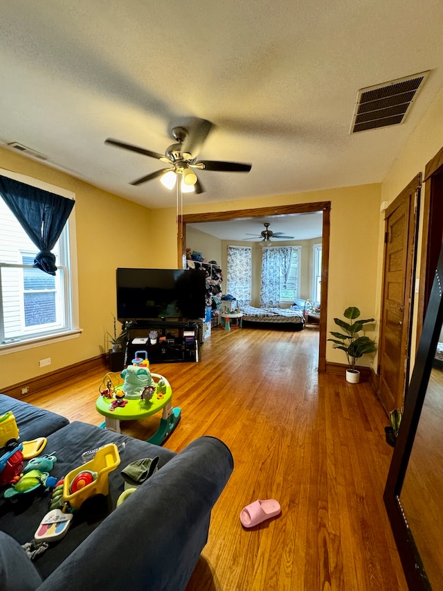 living room with ceiling fan, a textured ceiling, and hardwood / wood-style floors