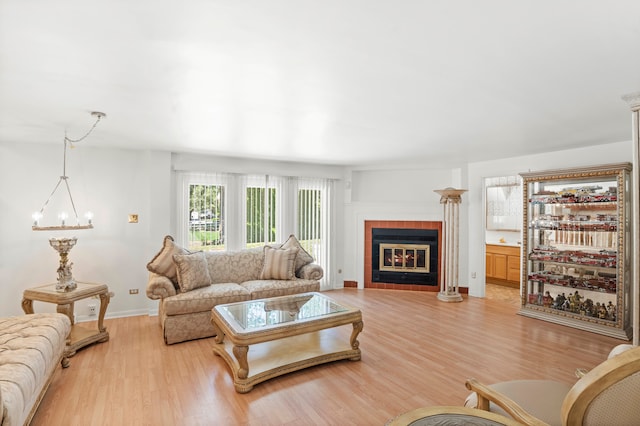 living room with a notable chandelier, a fireplace, and light wood-type flooring