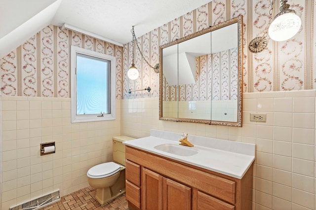 bathroom with tile walls, toilet, tile patterned floors, vanity, and backsplash