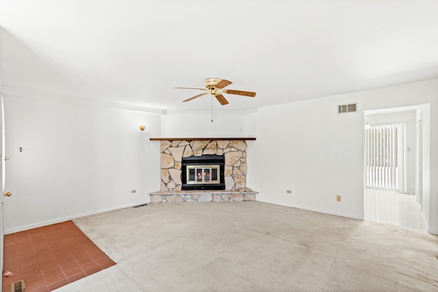 unfurnished living room with ceiling fan, a stone fireplace, and carpet