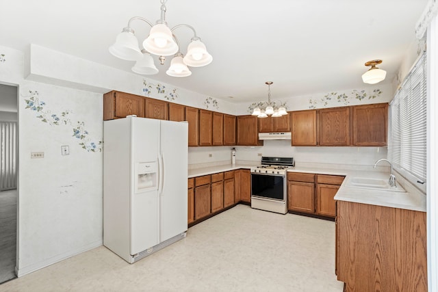 kitchen with a notable chandelier, white appliances, sink, and pendant lighting