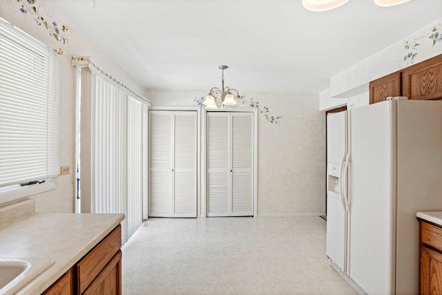 kitchen with light tile patterned floors, white refrigerator with ice dispenser, a chandelier, and hanging light fixtures