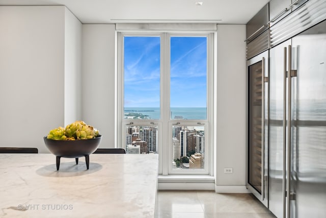 interior space featuring light tile patterned flooring, a water view, and a view of the beach