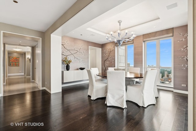 dining area with a tray ceiling, baseboards, an inviting chandelier, and wood finished floors