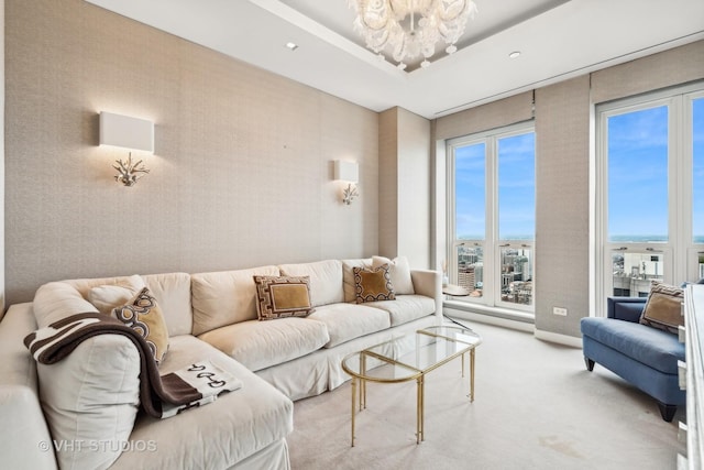 living area with carpet, a tray ceiling, an inviting chandelier, and wallpapered walls