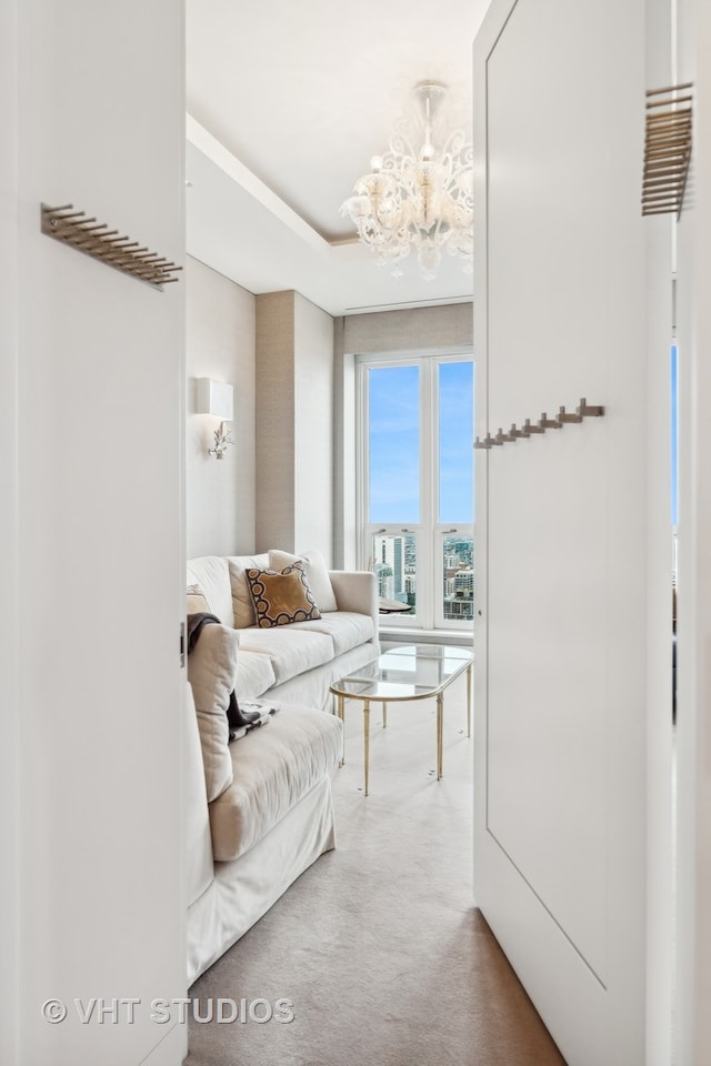 carpeted living room featuring a notable chandelier and a tray ceiling