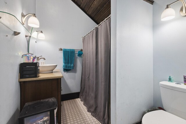 bathroom featuring toilet, tile patterned floors, vanity, and vaulted ceiling