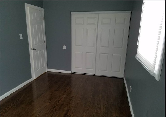 unfurnished bedroom featuring dark hardwood / wood-style flooring and a closet