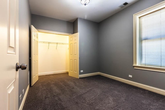 unfurnished bedroom featuring a closet and dark colored carpet