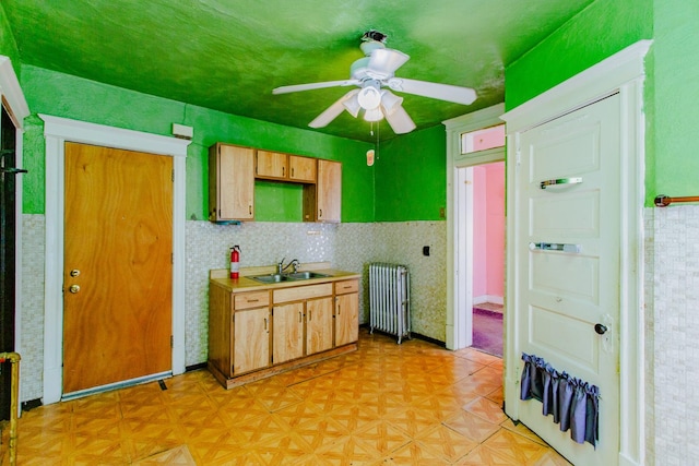 kitchen with light brown cabinets, sink, radiator heating unit, and ceiling fan