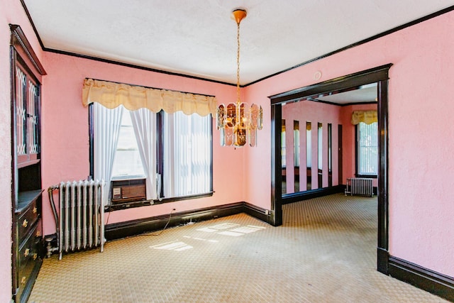 carpeted spare room with ornamental molding, radiator, cooling unit, and a chandelier