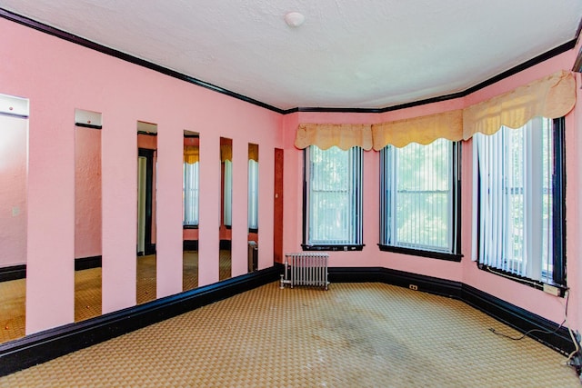 carpeted spare room with crown molding, radiator heating unit, and a textured ceiling