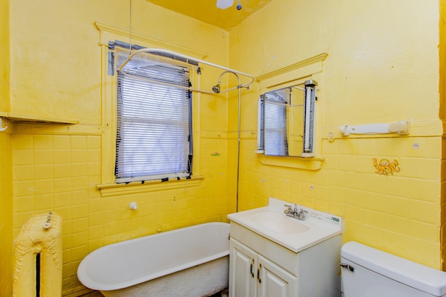 bathroom with vanity, a bath, tile walls, and toilet