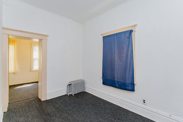 spare room with radiator heating unit and dark carpet