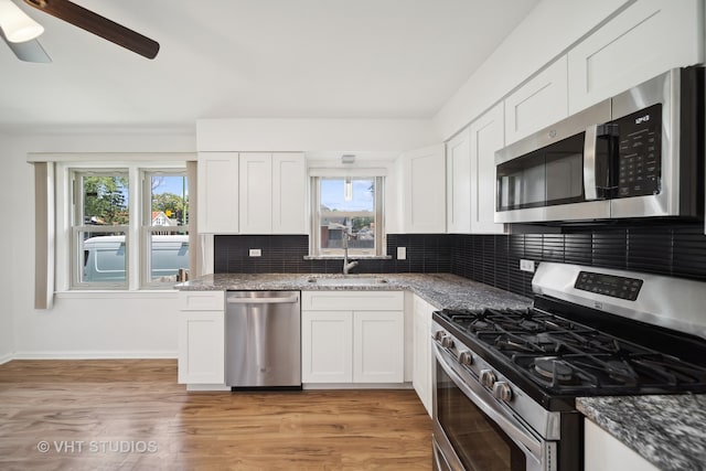 kitchen featuring light hardwood / wood-style flooring, appliances with stainless steel finishes, white cabinets, and backsplash