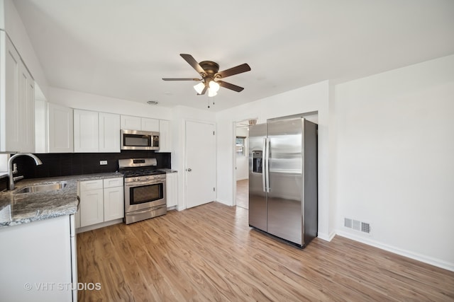 kitchen featuring light hardwood / wood-style flooring, sink, stainless steel appliances, and decorative backsplash