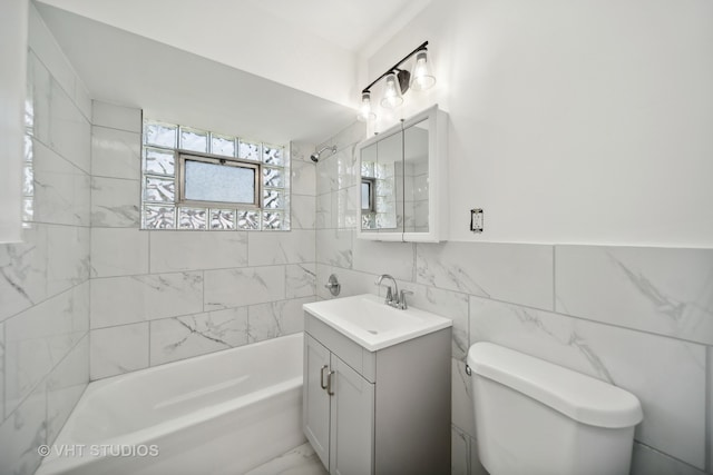 full bathroom with vanity, tile walls, toilet, and tiled shower / bath combo