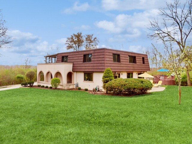 rear view of property with a yard and a balcony