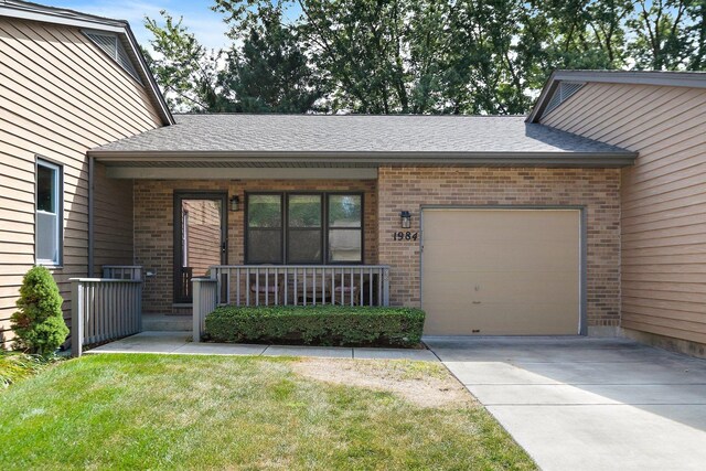 view of front of house featuring covered porch, a front yard, and a garage