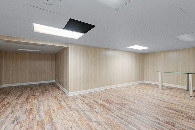 basement with a paneled ceiling and light hardwood / wood-style flooring