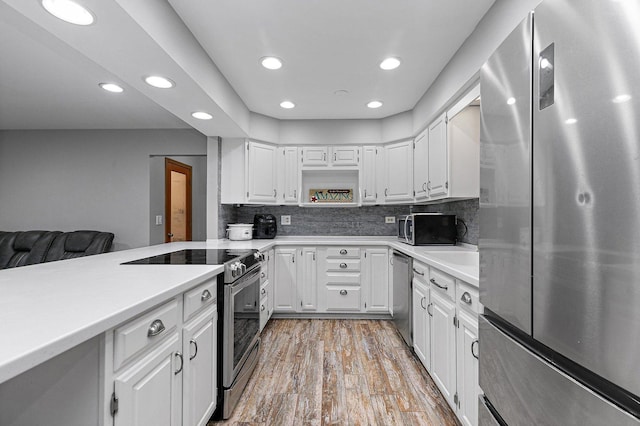 kitchen with appliances with stainless steel finishes, light wood-type flooring, decorative backsplash, and white cabinets