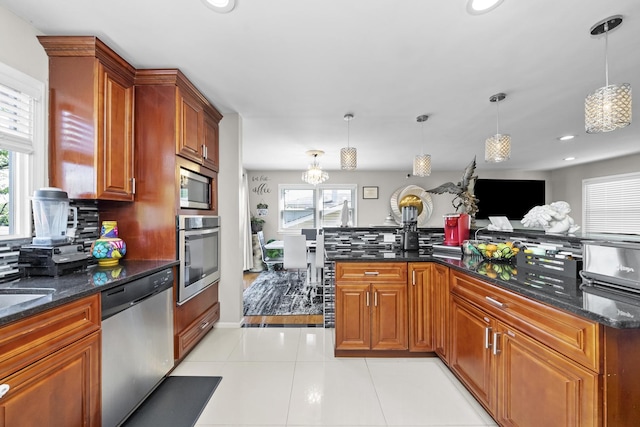 kitchen with pendant lighting, light tile patterned floors, dark stone counters, and appliances with stainless steel finishes