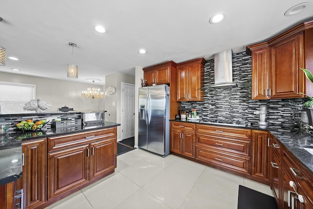 kitchen featuring tasteful backsplash, decorative light fixtures, appliances with stainless steel finishes, dark stone counters, and wall chimney range hood