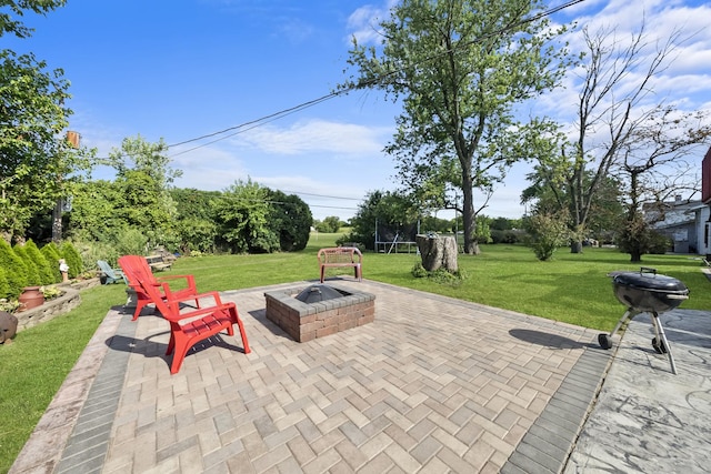 view of patio featuring a trampoline, grilling area, and a fire pit