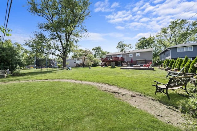 view of yard featuring a patio, a deck, a fire pit, and a trampoline