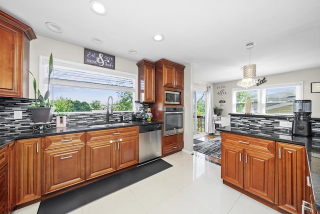 kitchen featuring appliances with stainless steel finishes, decorative light fixtures, tasteful backsplash, sink, and dark stone counters