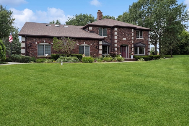 view of front of house featuring a front yard, a shingled roof, a chimney, and brick siding