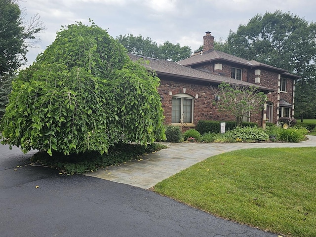 view of home's exterior with a yard, brick siding, and a chimney