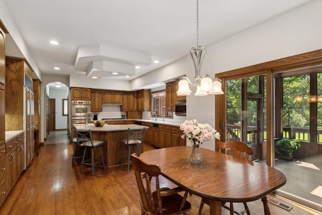 dining area featuring arched walkways, recessed lighting, wood finished floors, visible vents, and an inviting chandelier