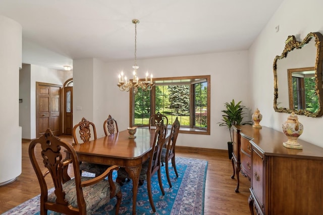 dining area with light wood-type flooring, an inviting chandelier, and baseboards