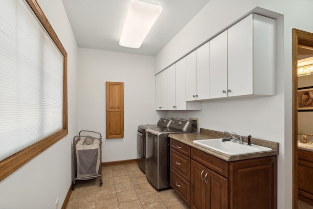 laundry room with a sink, washing machine and dryer, cabinet space, and baseboards