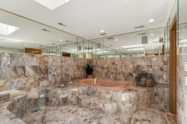 full bathroom featuring visible vents, a garden tub, and tile walls