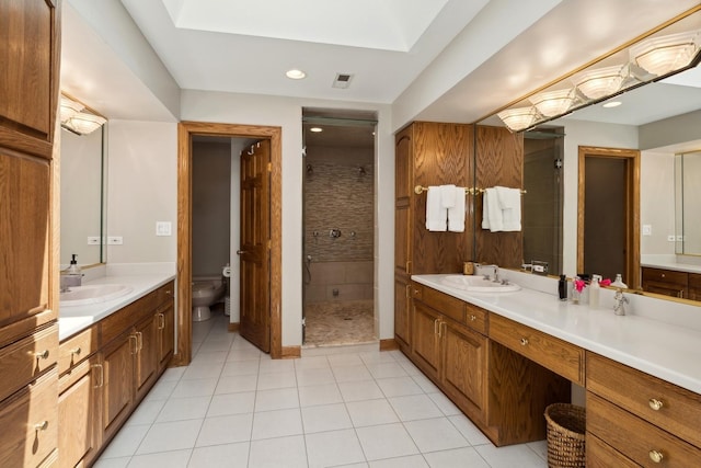 bathroom featuring a stall shower, two vanities, a sink, and toilet