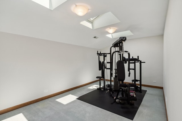 exercise room with carpet floors, lofted ceiling with skylight, visible vents, and baseboards