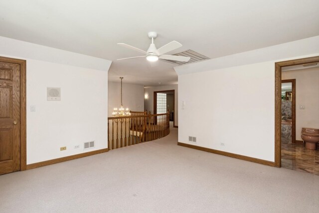 spare room featuring ceiling fan with notable chandelier, carpet, visible vents, and baseboards