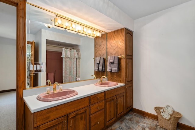 full bath with double vanity, baseboards, and a sink