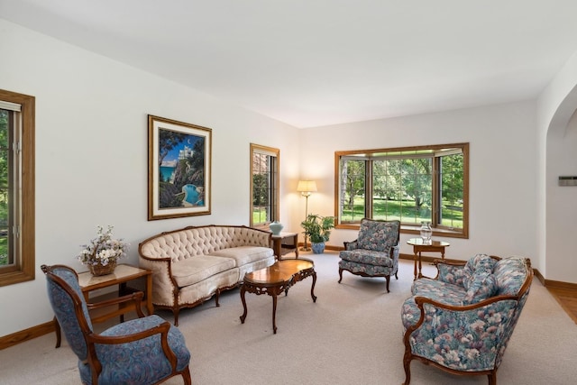 carpeted living room featuring arched walkways and baseboards