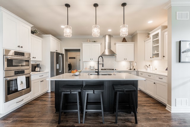 kitchen with appliances with stainless steel finishes, decorative backsplash, dark wood-type flooring, and wall chimney range hood