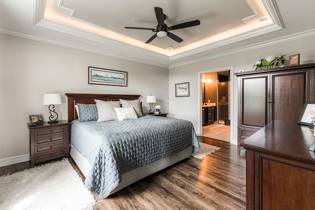 bedroom with ensuite bathroom, hardwood / wood-style flooring, a raised ceiling, and ceiling fan