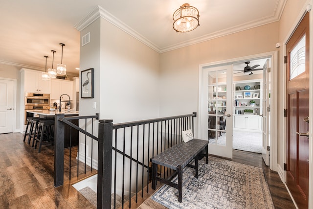 foyer entrance featuring ceiling fan with notable chandelier, dark hardwood / wood-style floors, and crown molding