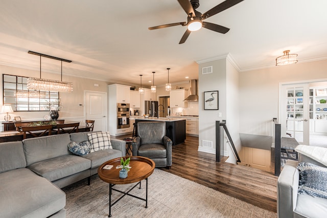 living room with ceiling fan with notable chandelier, crown molding, hardwood / wood-style flooring, and a wealth of natural light