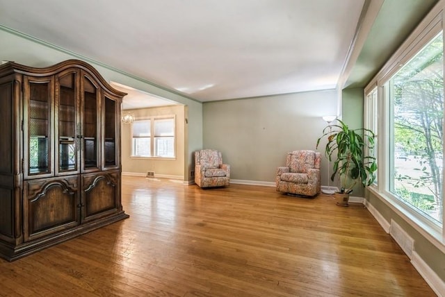 unfurnished room with wood finished floors, visible vents, a wealth of natural light, and baseboards