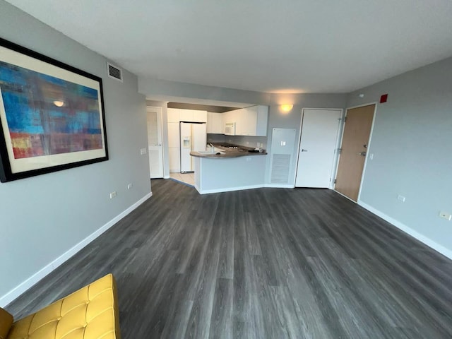 unfurnished living room featuring dark wood-type flooring, visible vents, and baseboards