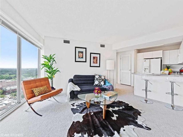 living area featuring light colored carpet and visible vents